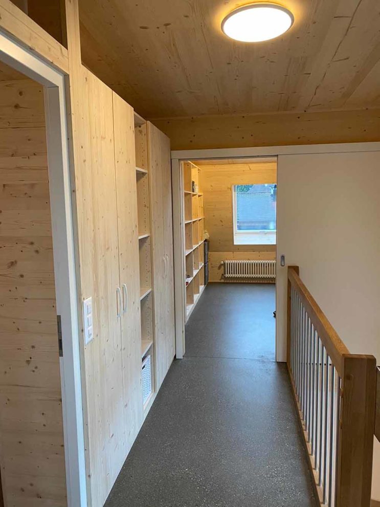 Fluransicht, grauer Flurboden, Einbauschränke aus Holz auf der linken Seite