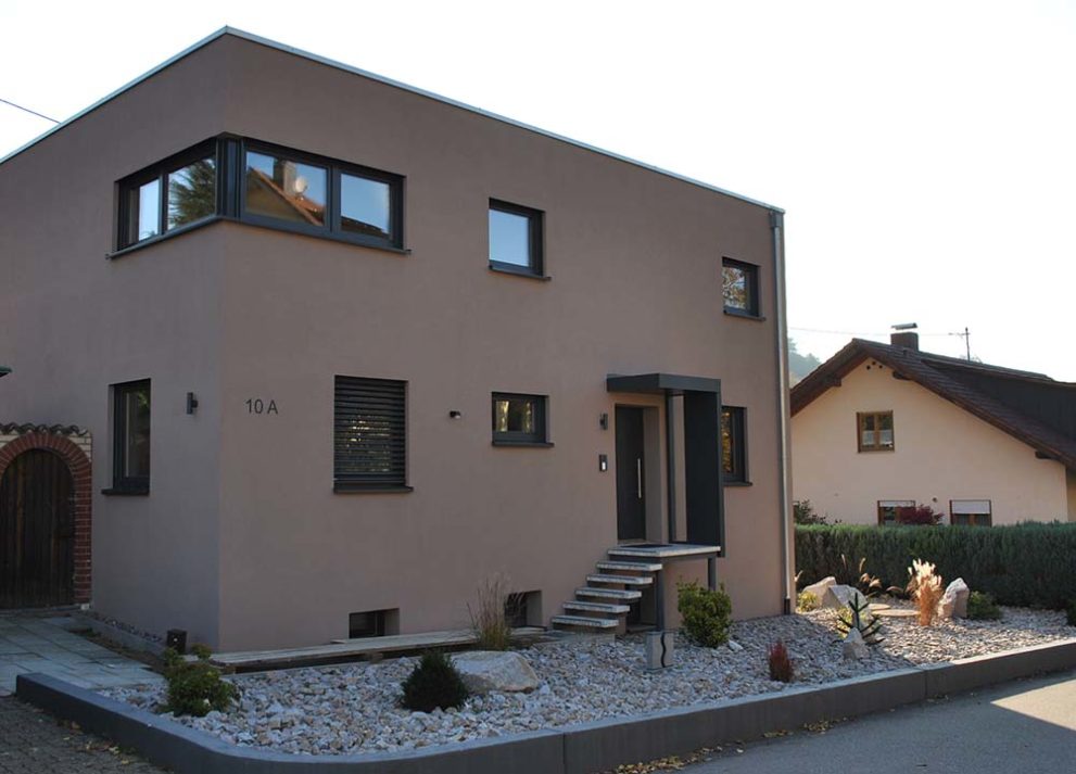 Braunes Haus mit Streppe zum Hauseingang und Kiesgarten