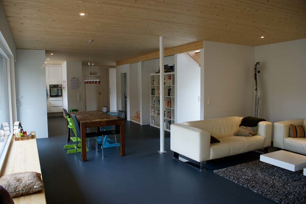 Wohn- und Esszimmeransicht - massiver Holztisch mit Stühlen und weißes Ledersofa