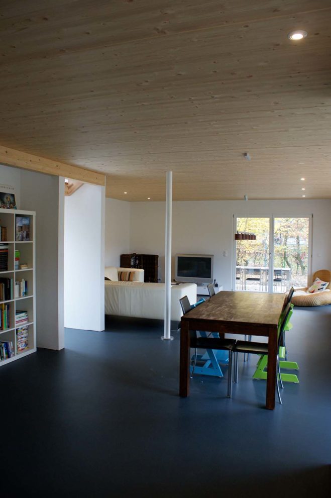 Wohn- und Esszimmeransicht - massiver Holztisch mit Stühlen und weißes Ledersofa im Hintergrund