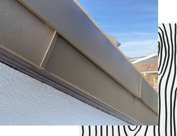 Graues Anschlussblech an einer Hauswand.