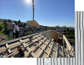 Arbeiter auf einem Dach, bei welchem gerade die Dachkonstruktion entsteht.