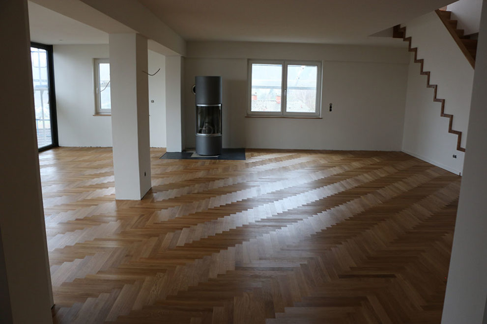 Wohnzimmer mit Holzofen, Holzboden und weißen Wänden