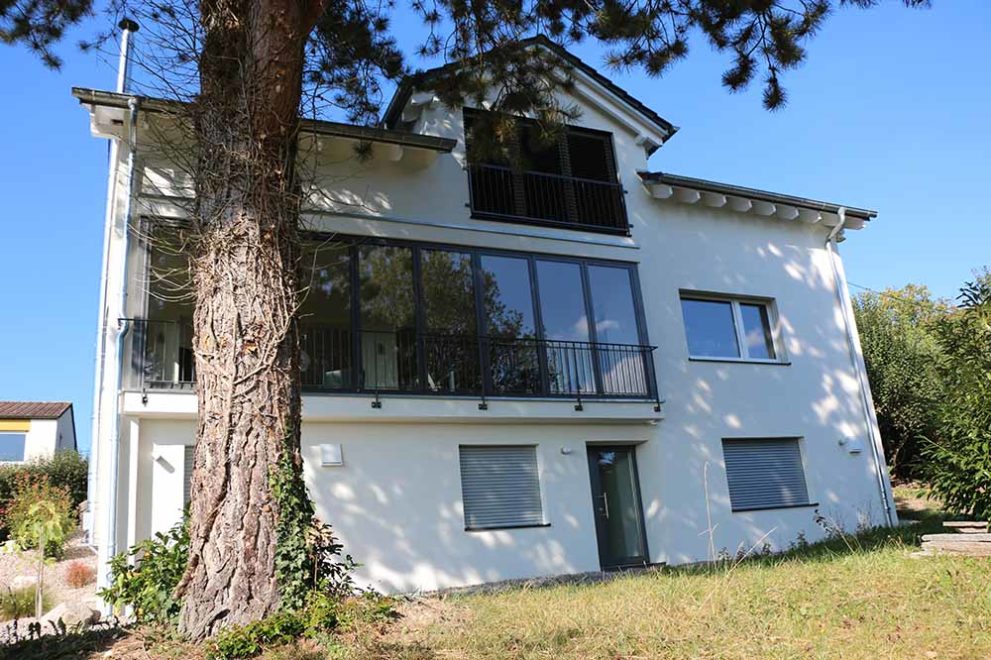 Weißes Haus mit großer Fensterfont und Garten