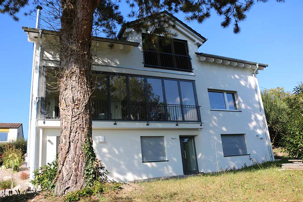 Weißes Haus mit großer Fensterfont und Garten