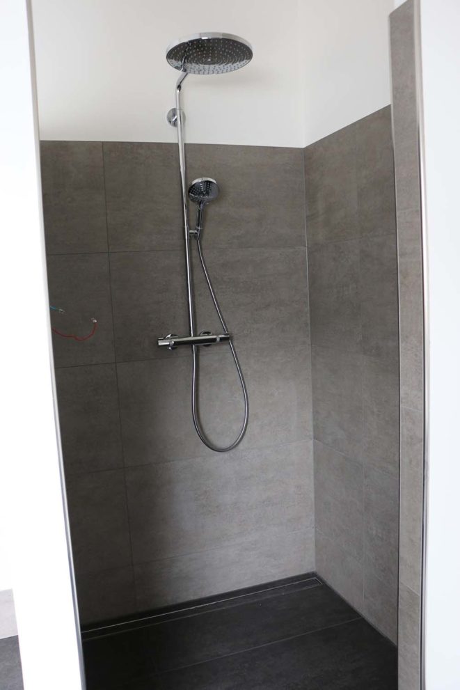 Dusche mit großem Duschkopf und grauen Fließen