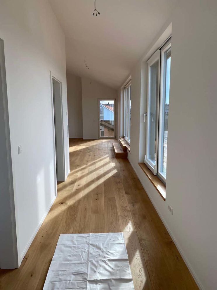 Flur mit Holzboden, weißen Wänden und großen Fenstern