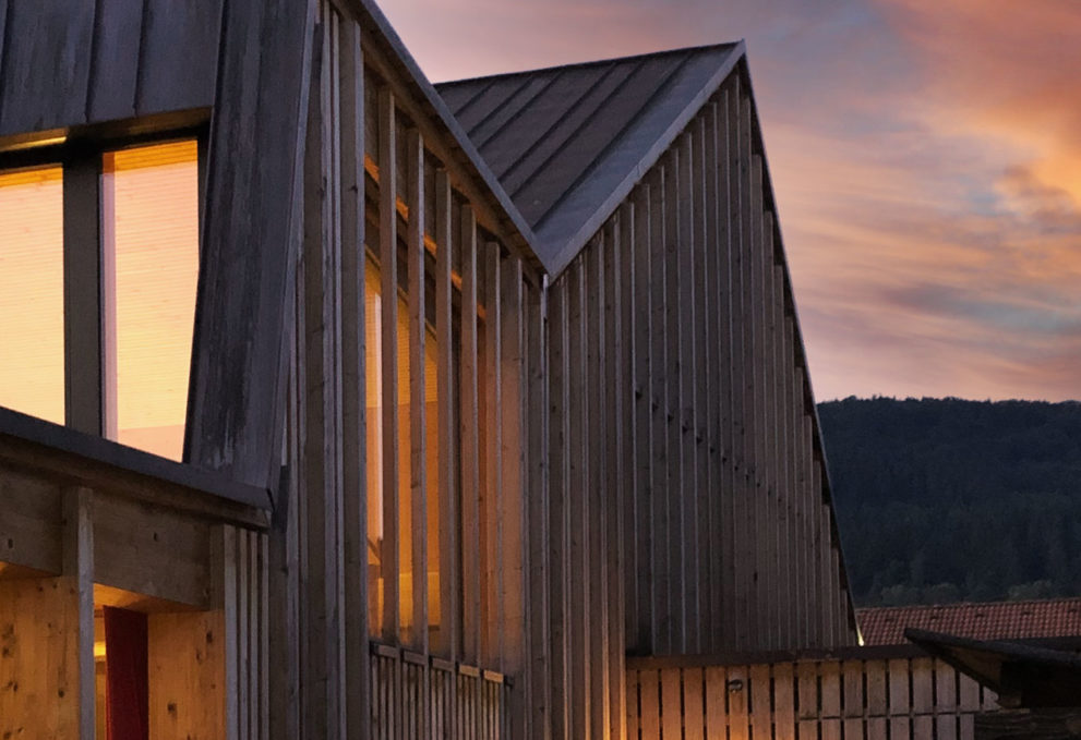 Ausschnitt eines Holzhaus mit Holzfassade bei Dämmerung.