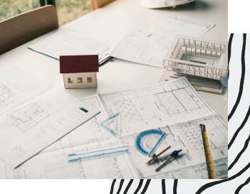 Tisch mit Bauplänen und kleinen Modellhäusern